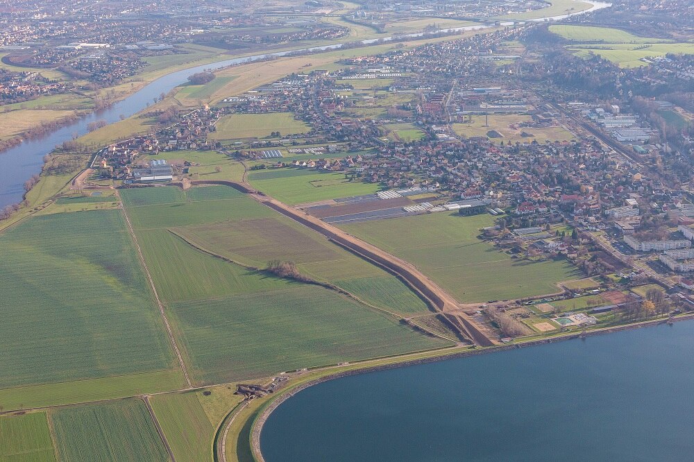 Luftbild einer Landschaft mit Fluss, Wiesen, Stadt und See