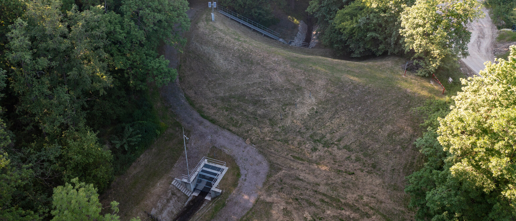 Luftbild vom Hochwasserrückhaltebecken umgeben von Wald