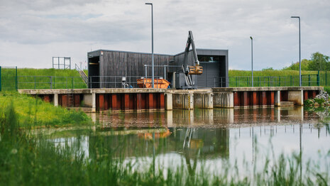 Blick vom Ufer eines Sees auf ein Gebäude auf der anderen Seite